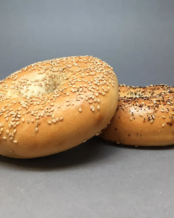 A sesame seed bagel in front of an everything bagel