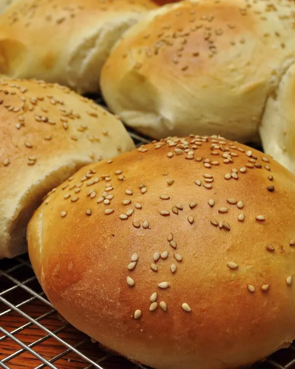 Sesame seed hamburger buns on a cooling rack
