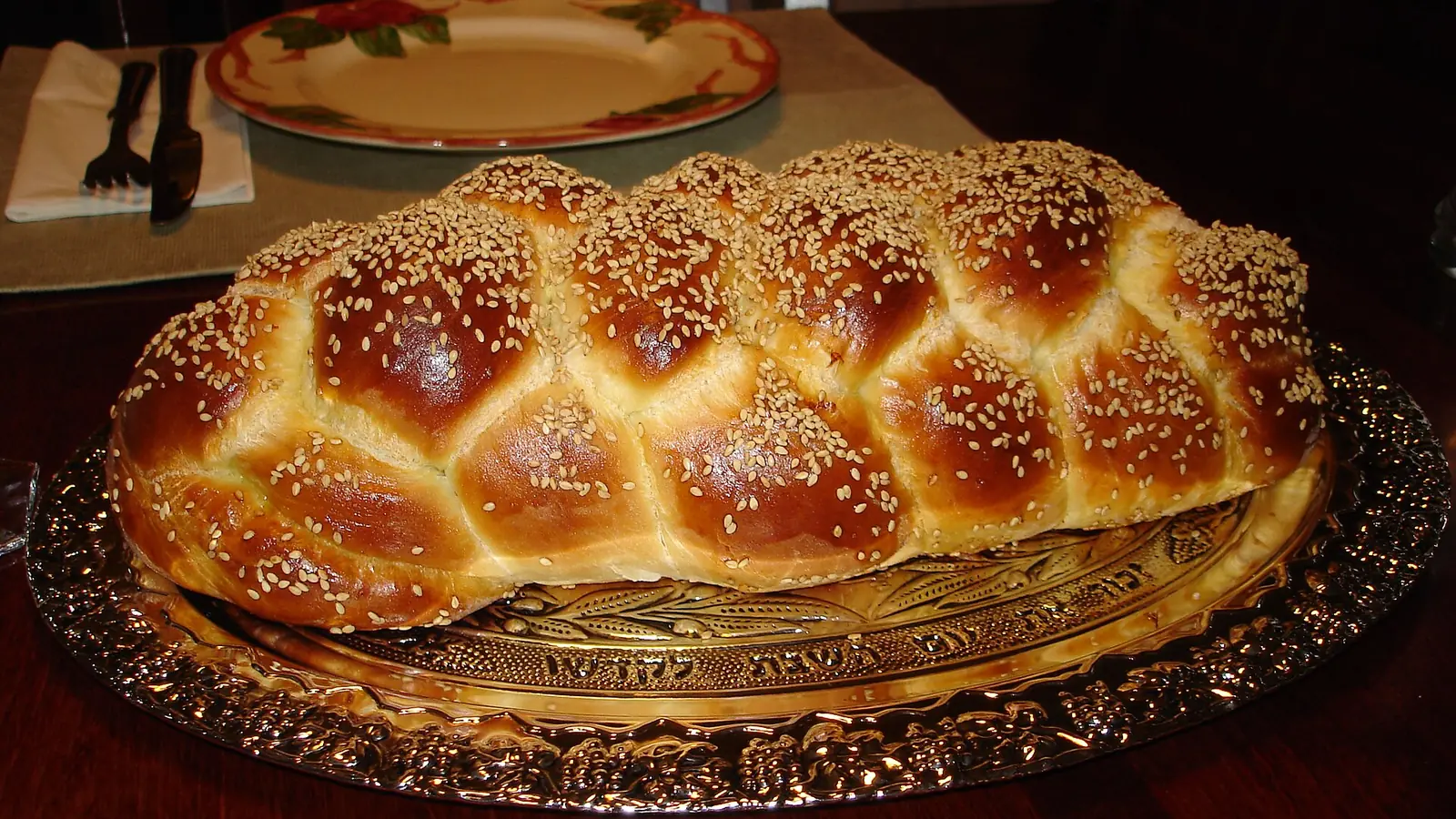 Six-braid challah with sesame seeds on a serving platter