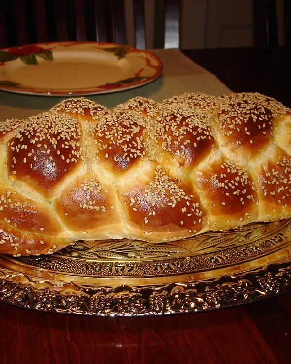 Six-braid challah with sesame seeds on a serving platter