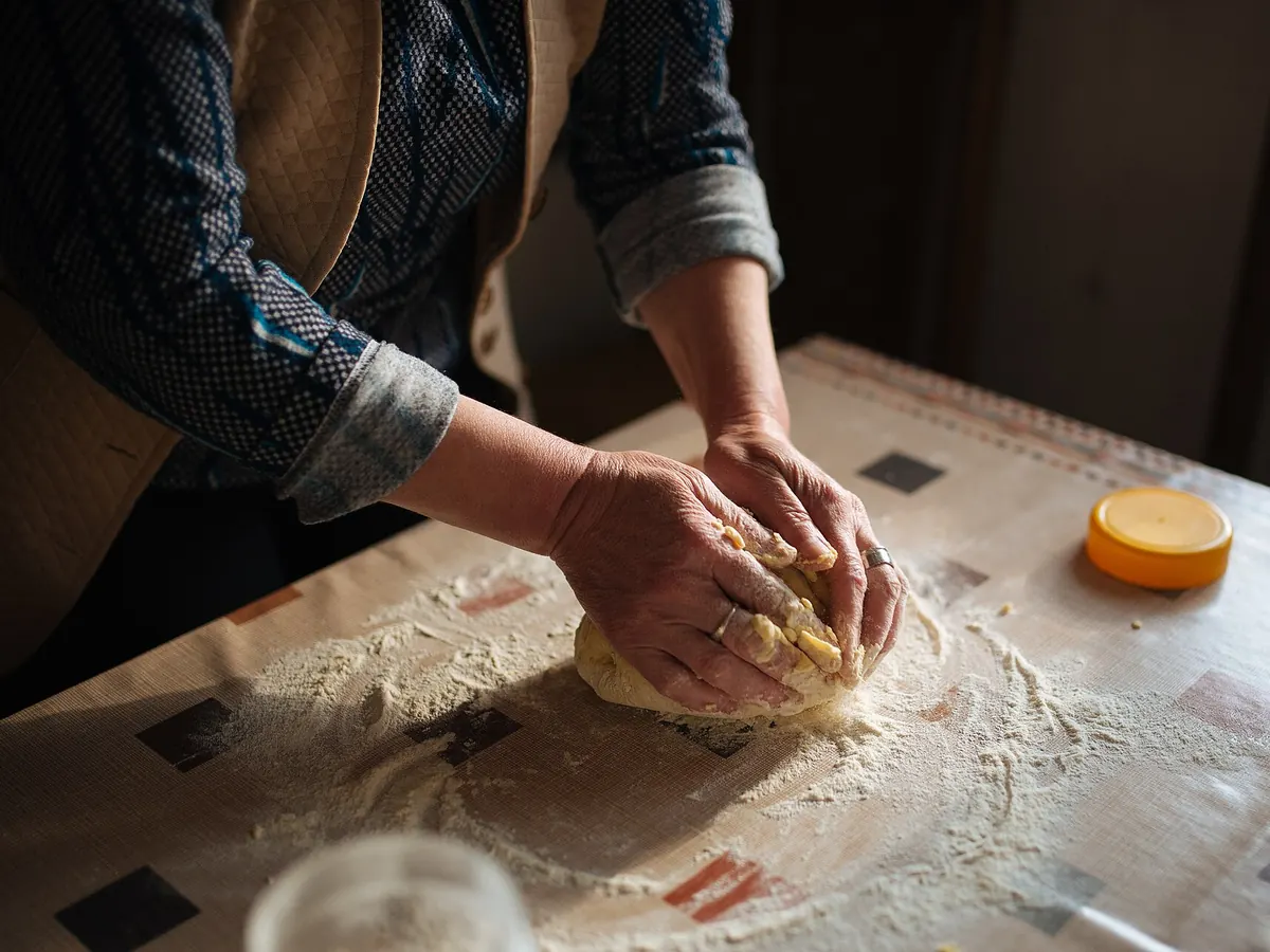 A baker’s hands kneading bread dough on a floured table